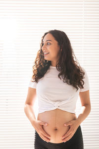 Portrait of beautiful young woman standing against wall