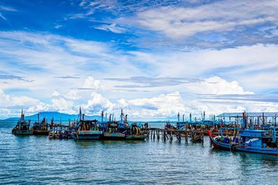 Boats in sea against cloudy sky