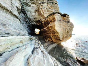 Rock formation on sea shore against sky