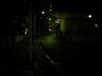 Empty road along illuminated street lights at night