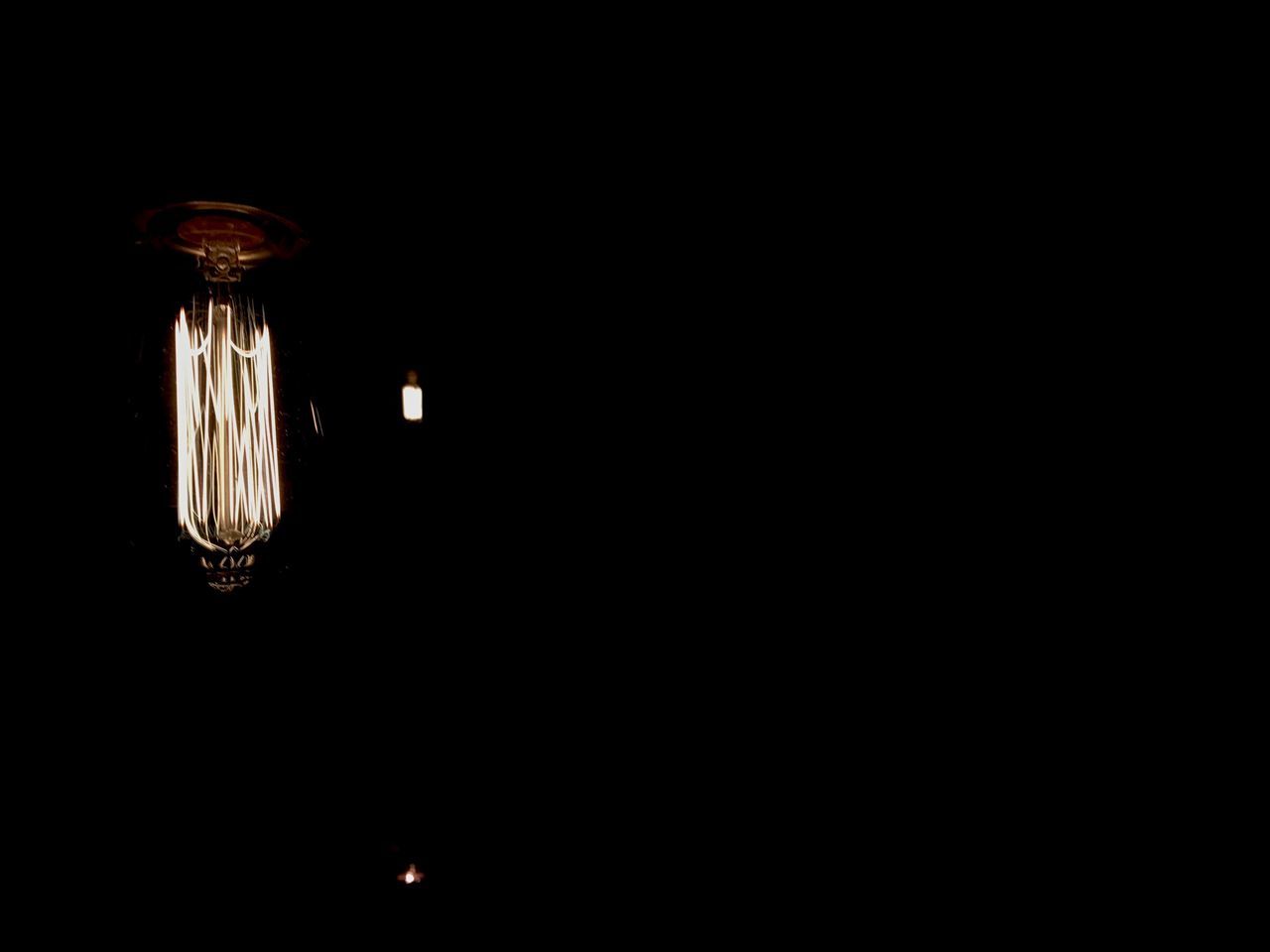 LOW ANGLE VIEW OF ILLUMINATED LIGHT BULB IN DARK