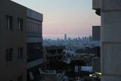 Modern buildings in city against sky at sunset