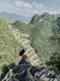 Rear view of man sitting on rock