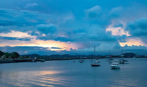 Sailboats in sea against sky at sunset