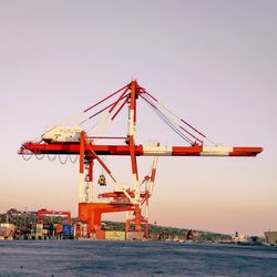 Cranes at commercial dock against clear sky