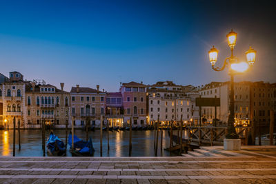 Illuminated buildings by street against sky at night