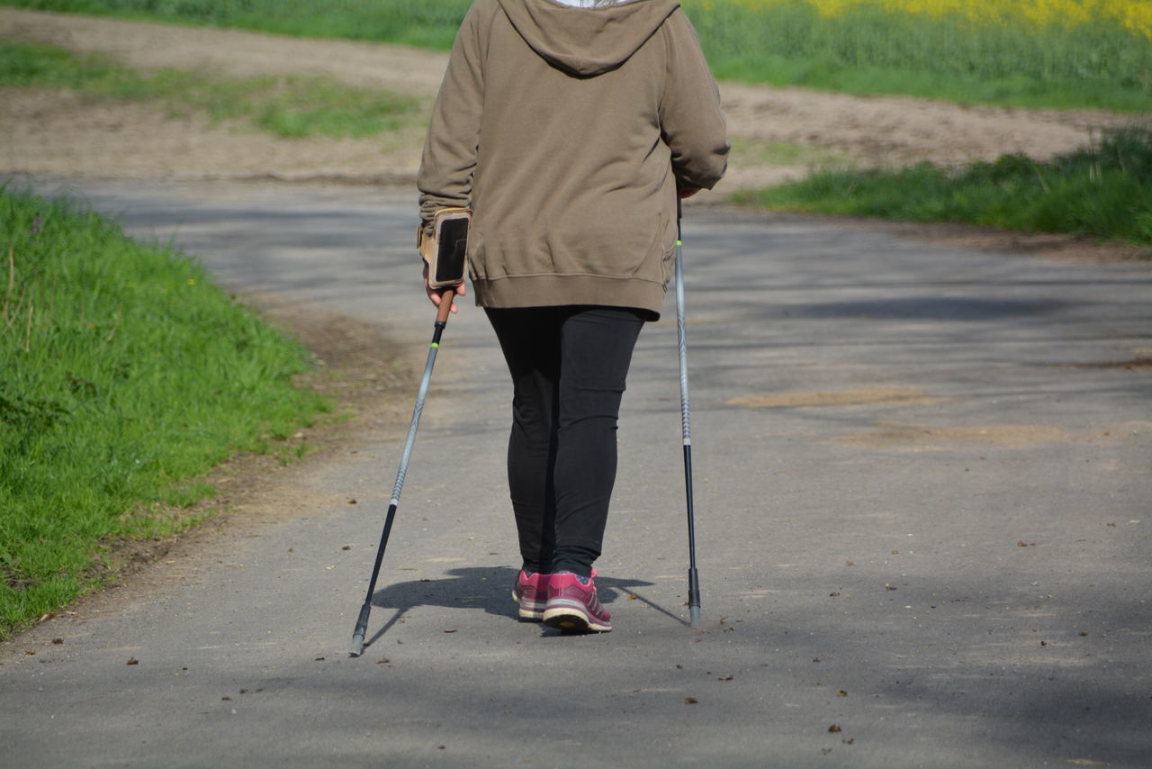 LOW SECTION OF MAN WALKING ON ROAD