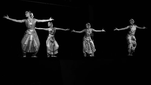 Rear view of women standing against black background