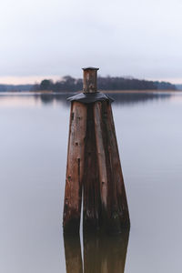 Wooden posts on lake against sky