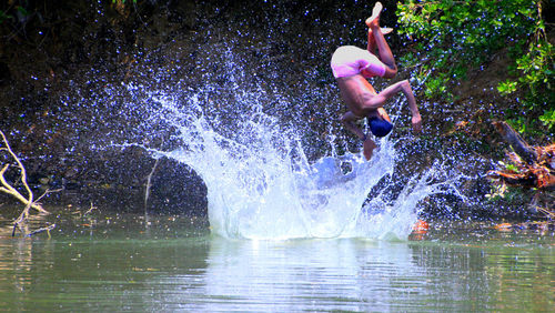 Full length of shirtless man jumping in water