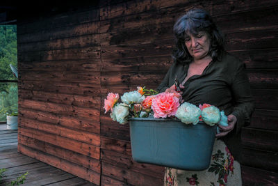 Senior woman holding flowers in bucket