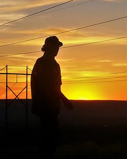 Silhouette of people standing against sunset