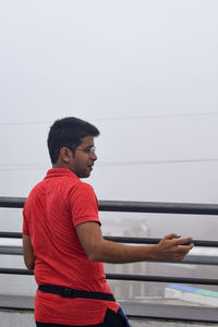 Side view of young man looking away against wall