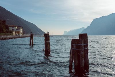 Wooden posts in sea against sky