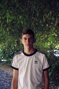 Portrait of young man standing against trees