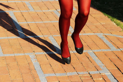 Low section of woman standing on red road