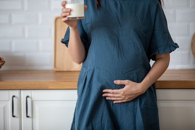 Midsection of pregnant woman holding milk glass