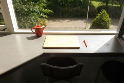 High angle view of cutting board and teapot against window on table