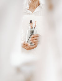 Midsection of woman holding thermometer