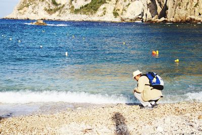 Rear view of men sitting on rock at beach