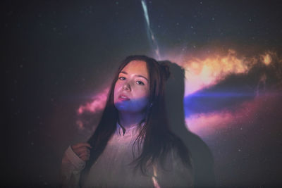 Portrait of beautiful young woman standing against star field at night