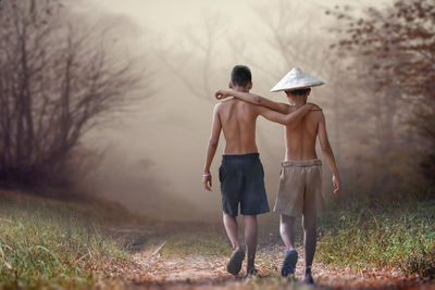 Rear view of men walking on field