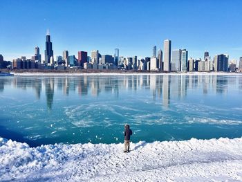 Man on beach against clear blue sky in city