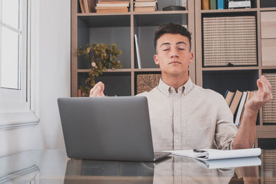 Young man using mobile phone while sitting on table