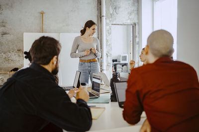 Female entrepreneur discussing with colleagues in startup company