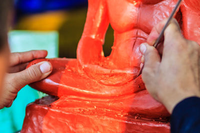 Cropped image of sculptor painting statue