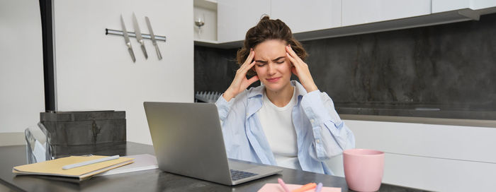 Side view of young woman using laptop while sitting on table