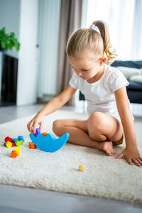 Side view of boy playing with toy on floor at home