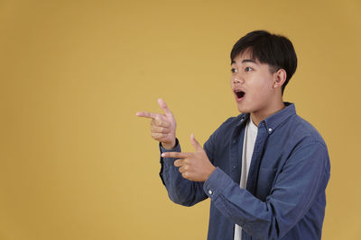 Man looking away while standing against yellow background