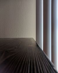 Close-up of wooden table by wall