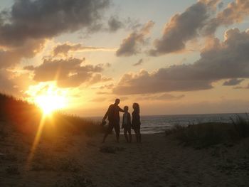 Silhouette of people on beach at sunset