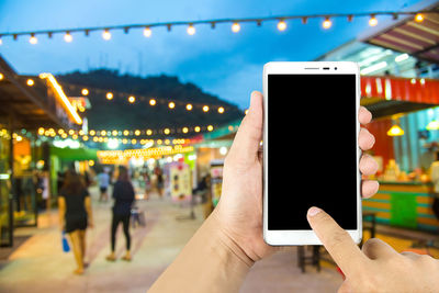 Cropped hand holding mobile phone at market