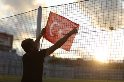 Man playing basketball against sky during sunset