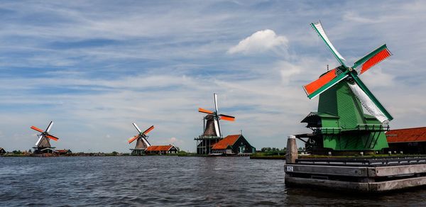 Traditional windmill by sea against sky