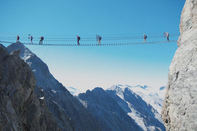 Low angle view of people on snowcapped mountains against clear sky