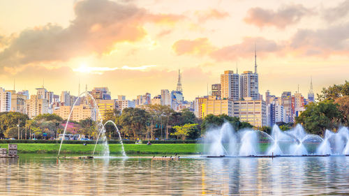 Fountain in city against sky during sunset