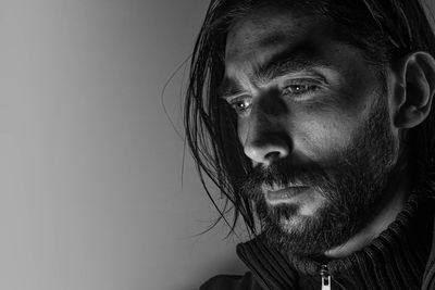 Close-up portrait of man looking away against gray background