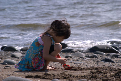 Rear view of girl sitting on beach