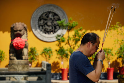 Side view of young man holding flower