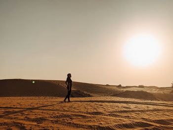 Man standing on desert against sky during sunset