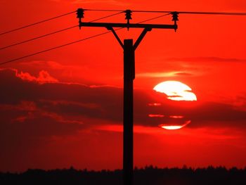 Silhouette of electricity pylon against sky during sunset