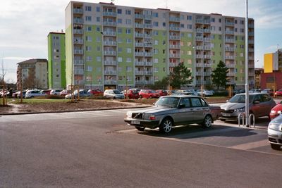 Cars on road by buildings in city against sky