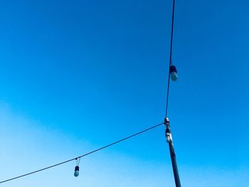 Low angle view of lighting equipment against clear blue sky