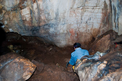 High angle rear view of man sitting on rock at night