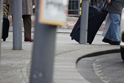 Low section of men with luggage walking on road