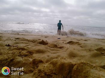 Rear view of man on beach against sky